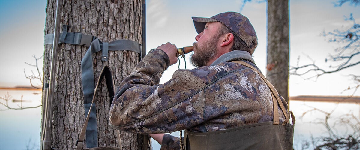 Man standing next to tree with duck call